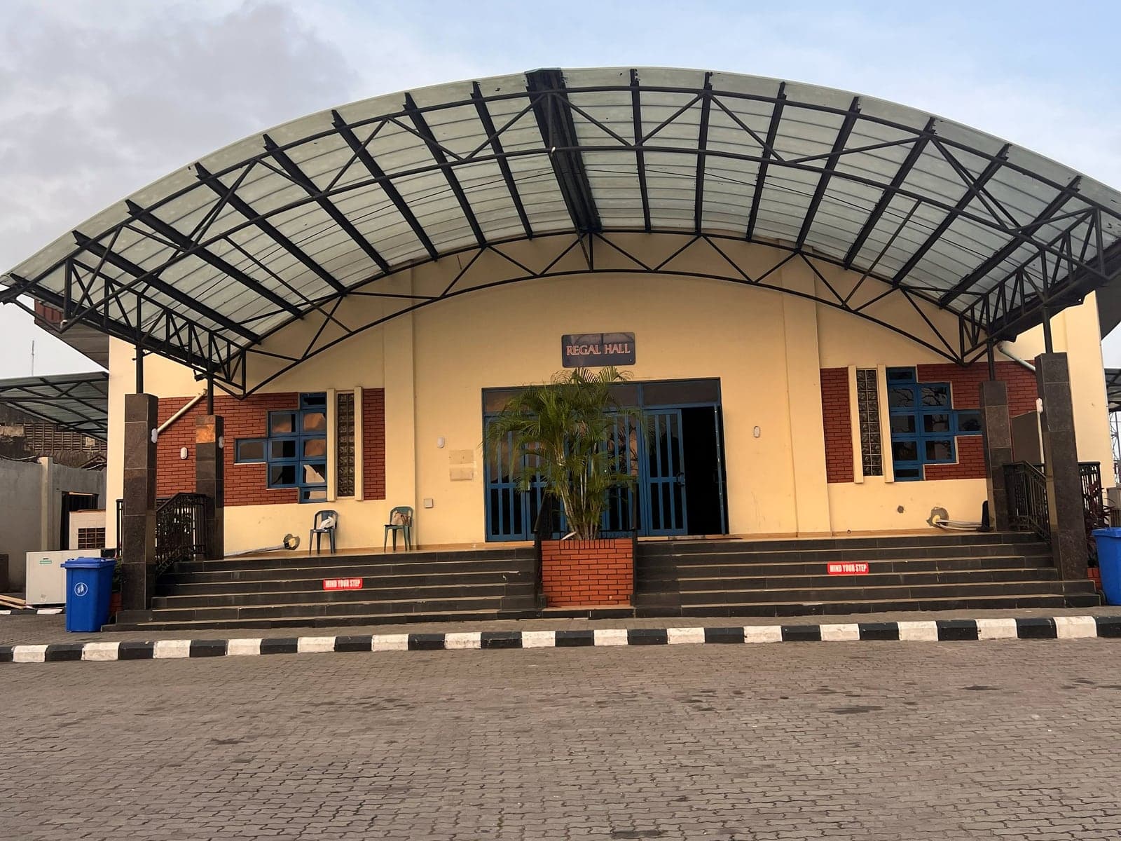 Regal Hall, Oregun: a barrel-vaulted steel canopy over the entrance, with a stepped approach and paved forecourt.